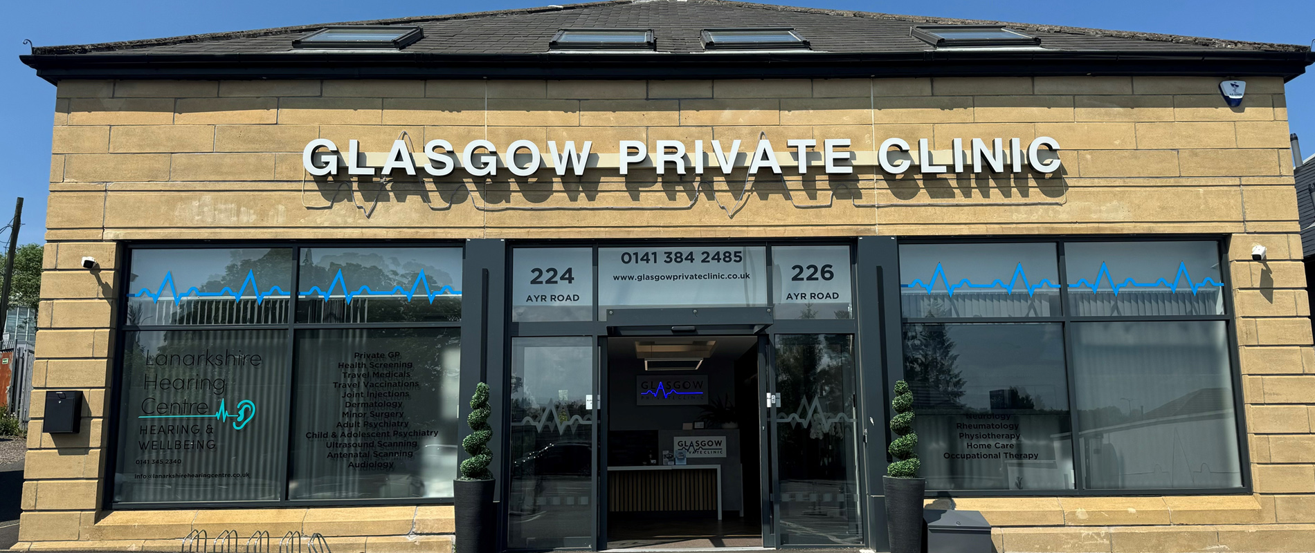 The Glasgow Private Clinic building on Ayr Road — blond sandstone, white channel lettering and the blue ECG line across every window